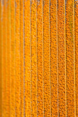 A bright orange textured rusty fence. Image has shallow depth of field and selective focus.