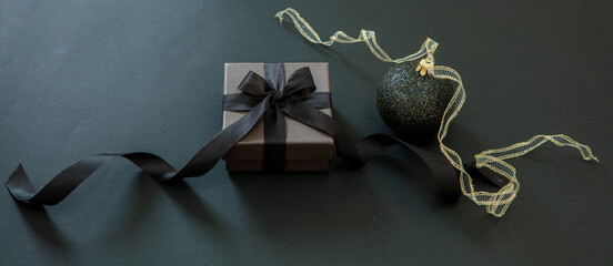 Black Friday and Christmas concept. Xmas bauble and gift box on black background, banner.