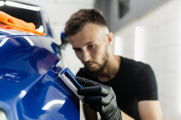 Process of applying ceramic protective coat on body car using sponge in detailing auto service. Car service worker apply ceramic coating to protect the car body from scratches.
