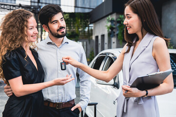 Couple picking up car from garage sales woman returning car keys to customers.