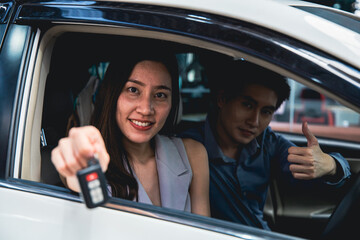 Obraz premium Asian couple customers bring the car to check the condition of the car at the garage and handed the car keys to the staff.