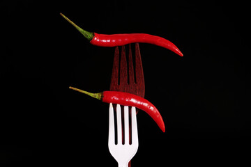 red chili Pepper on wooden fork on black background
