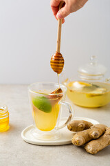 Winter ginger spice and fruits tea in glass cup pouring honey food