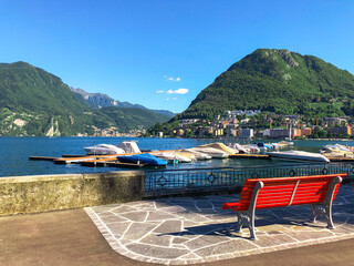 Stunning landscape of picturesque Lake Lugano and the green lush Swiss Alps in the distance. Idyllic town Lugano, Switzerland, on a sunny summer day.