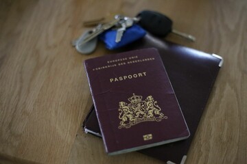 Biometric passport of the Netherlands and bunch of keys on the table
