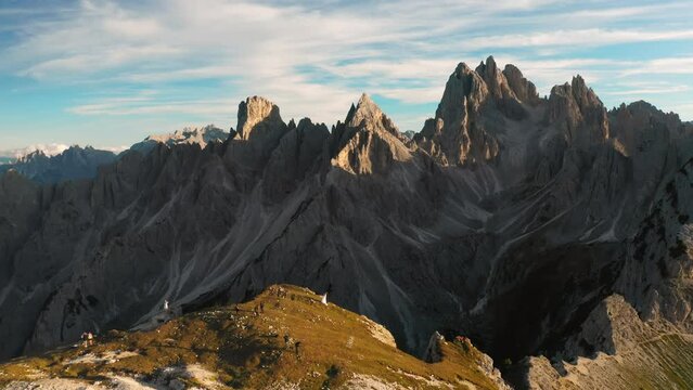 Newlyweds take wedding photos and videos on top of mountain against cliff at sunset. Three Peaks of Lavaredo under blue sky aerial view