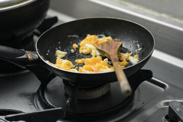 preparation of scrambled eggs, in a typical colombian breakfast with a wooden spoon in a small black sarter
