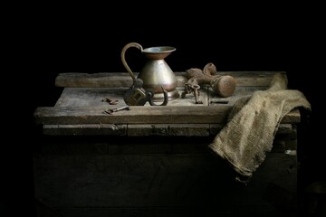 Collection of antique items in a dimly lit room with a flagon, wax stamp, open padlock, and keys