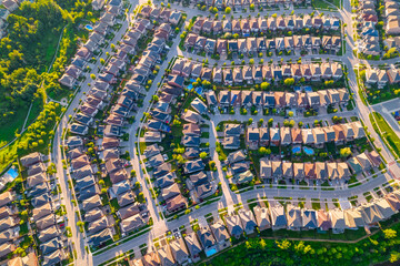 Aerial view of middle class residential houses at summer evening. American neighbourhood suburb. Residential houses and homes build in strong pattern to each other. Real estate.