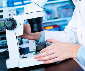 A young woman is testing an electronic module for the production of electric cars. Quality control...