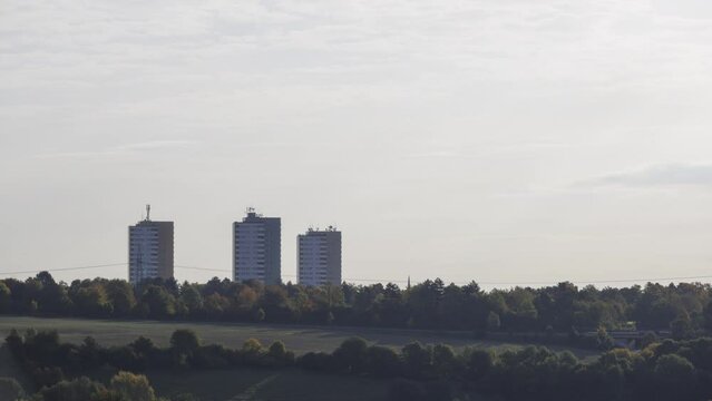 Time lapse shot of colorful trees and three apartment buildings on a misty morning in autumn