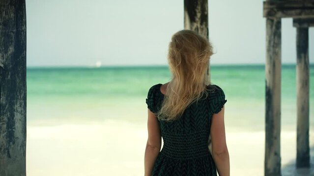 tanned woman in dress walking on beach