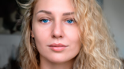 Portrait of an attractive charming smiling young woman with curly white hair and blue eyes looking away. Healthy hair. Clear glowing skin