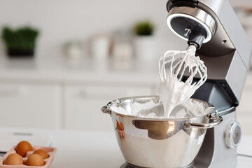 On the table is a mixer with white meringue cream inside. Homemade sweets. High quality photo