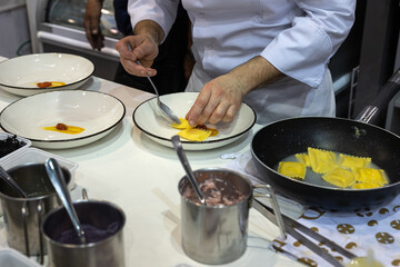 Chef of a Restaurant who is going to Plate the Freshly Cooked Italian Pasta Specialty - Dishes already Stuffed with Toppings