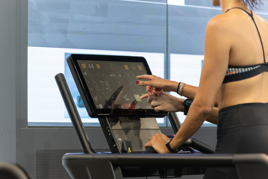 Girl Touching a Display of Modern Treadmill in Fitness Club during her Workout in Fitness Club