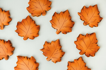 Gingerbread cookies with orange icing in the shape of fallen autumn leaves freshly baked out of the oven. Thanksgiving Day or Halloween festive background. Flat lay. White background