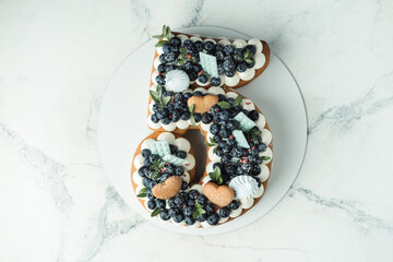 Birthday layered cake in the shape of digit 5 with cream cheese filling decorated with blueberries. White background - obrazy, fototapety, plakaty