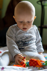 chłopiec w wieku niemowlęcym siedzi i bawi się zabawkami. Zabawki - gryzaki dla niemowląt. 