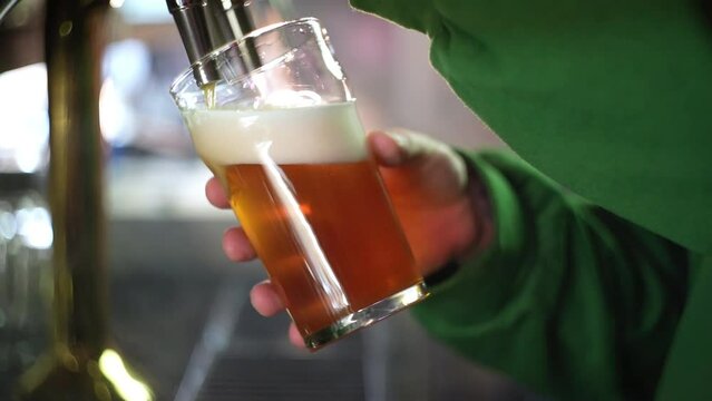 Bearded barman pooring beer from a tap in slow motion