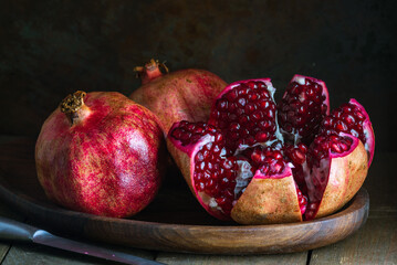 pomegranate seeds fruit Fresh ripe wooden  background open dark vintage background still life organic Red vitamins wooden plate table closeup sweet.