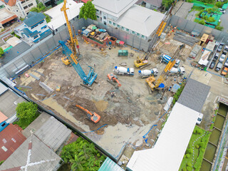 Aerial view of busy industrial under construction site workers working with cranes and excavators. Top view of precast concrete slap floor full of steel. Development high rise architecture building.