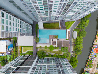 Aerial view of a condominium with swimming pool and sky garden. Top of high rise residential architecture building in urban city, Bangkok Downtown, Thailand.