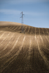 A power line trellis is planted in the middle of a field
