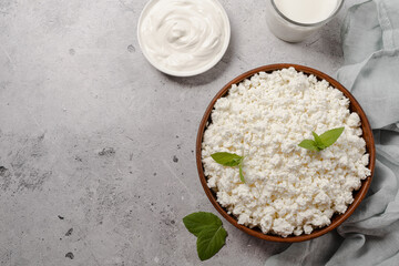 Cottage curd cheese in a wooden bowl on grey table.