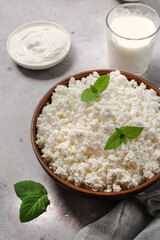 Cottage curd cheese in a wooden bowl on grey table.
