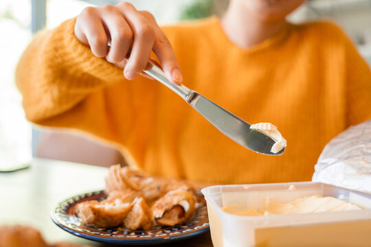 Unknown Woman Wearing Orange Jumper Holding Knife With Butter