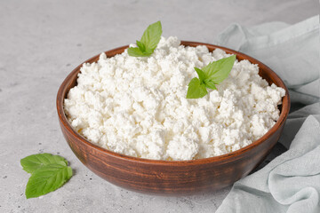 Cottage curd cheese in a wooden bowl on grey table.