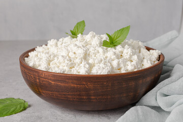 Cottage curd cheese in a wooden bowl on grey table.