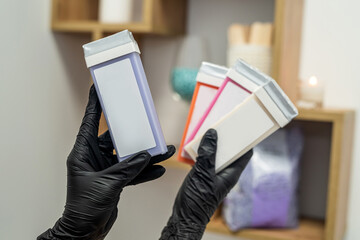 hand of a beautician holding fat-soluble wax cartridges for hair removal.