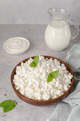 Cottage curd cheese in a wooden bowl on grey table.