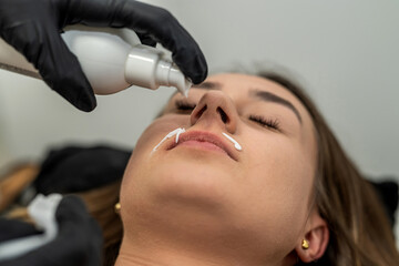 master applies a soothing cream after epilation of the upper lip.