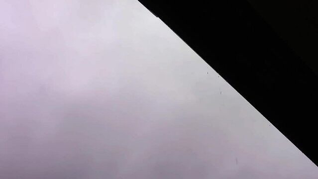 Rain drops falling from roof on rainy day, high contrast autumn background with copy space