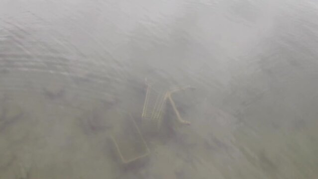 Empty shopping trolley under water in lake, global warming and environmental pollution concept, garbage in waste water, climate change danger