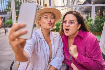 Obraz premium Body positive female friends making selfie at the smartphone camera