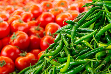 Green hot peppers and tomatoes on the market counter.