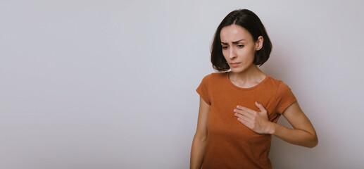 Young woman suffering from heart attack isolated on gray background