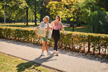 Cute besties walking talking after workout at the summer park