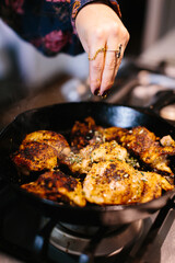 organic chicken thighs cooking  in a cast iron skillet