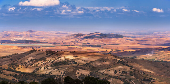 Wide angle view of the vast panorama of cultivated fields, productive settlements, hills and sea, taken from the archaeological site of Morgantina in Sicily
