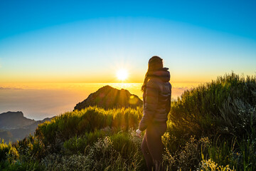 Woman enjoying beautiful mountain landscape of Pico do Ariero during sunrise. Pico do Arieiro,...