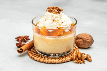 dessert with pumpkin, whipped cream. Pumpkin parfait with nuts in glass on a light background. banner, menu, recipe place for text, top view