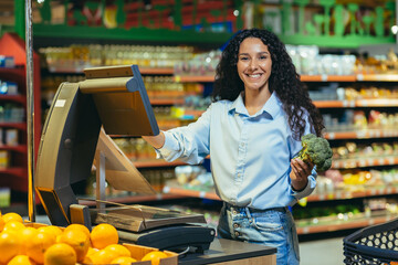 Portrait of a happy shopper in a supermarket in the fruit and vegetable section, hispanic woman...