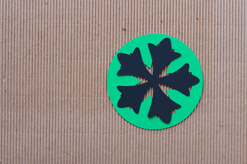 black asterisk on green paper disc on corrugated cardboard