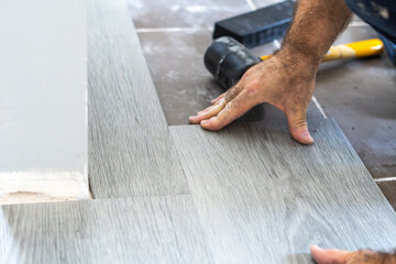 Male hands working laying vinyl parquet on the floor