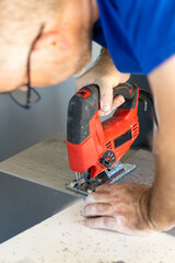 Professional carpenter cutting vinyl boards with an electric jig saw.